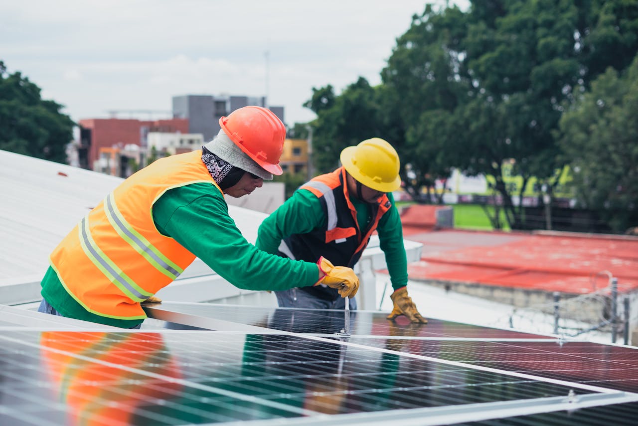 hero-img Two workers installing rooftop solar panels safely equipped with PPE and tools.