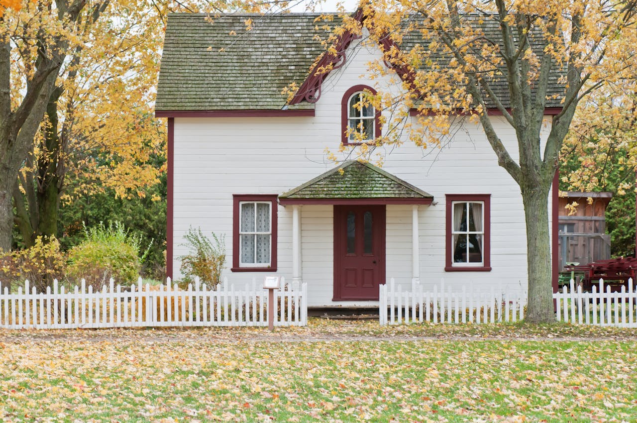 Home Picturesque traditional house with autumn foliage and a white picket fence in London, Ontario.