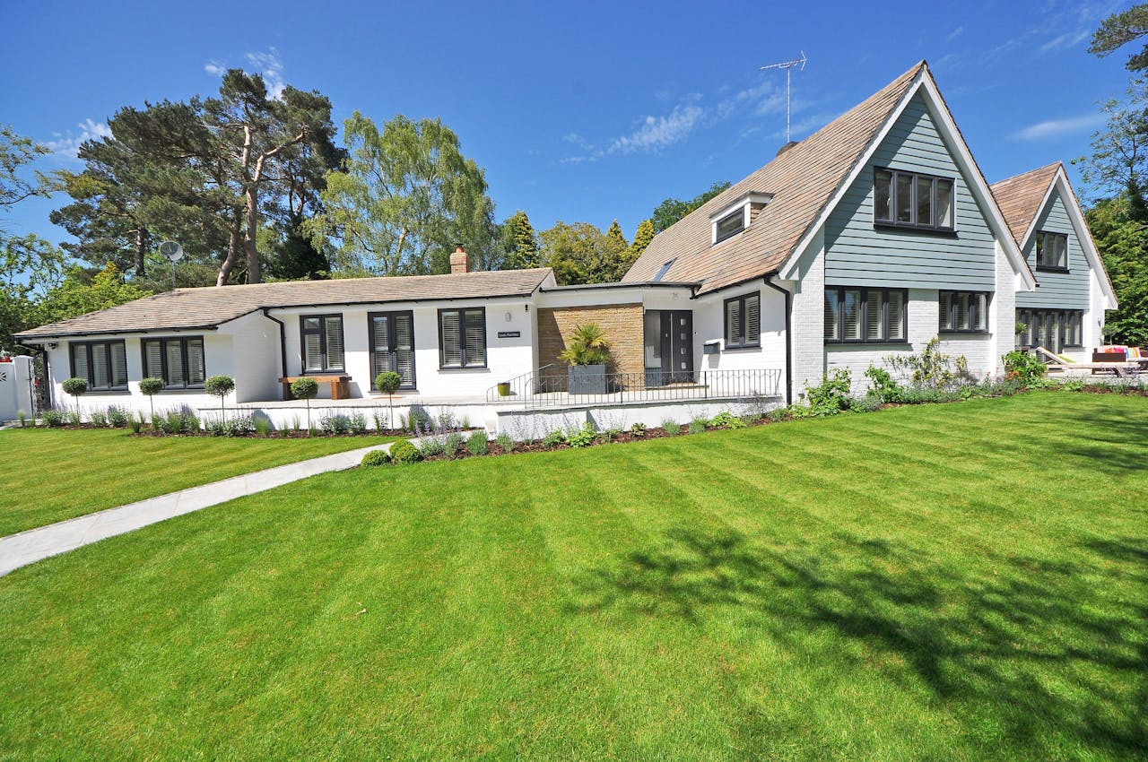why-choose-us Contemporary house exterior with large manicured lawn and beautiful garden.